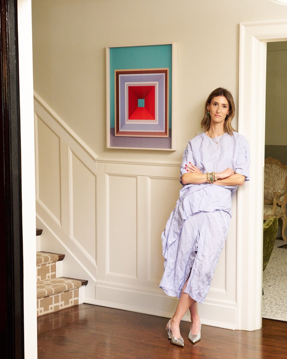A framed geometric painting hung in a home stairwell, with Jo Jo Whitefield standing beside it